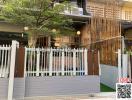 Modern residential building exterior with a bamboo facade and grey fence