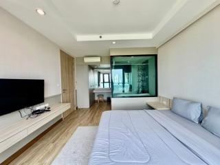Spacious bedroom with large bed, modern décor, and natural light streaming through glass doors