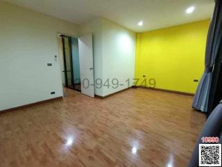 Spacious bedroom with glossy wooden flooring and bright yellow accent wall