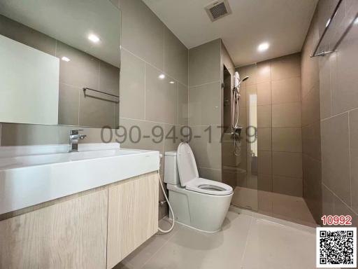 Modern bathroom interior with a vanity cabinet, sink, toilet, and tiled walls