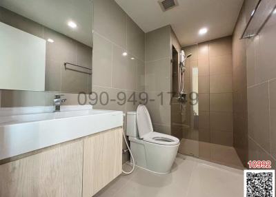 Modern bathroom interior with a vanity cabinet, sink, toilet, and tiled walls