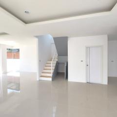 Spacious and bright unfurnished living space with staircase and glossy tiled flooring