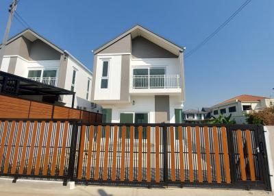 Modern two-story residential house with balcony and gated fence