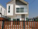 Modern two-story house with a balcony and fencing