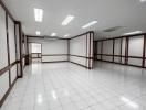 Spacious and well-lit empty commercial space with white tiling and fluorescent lighting