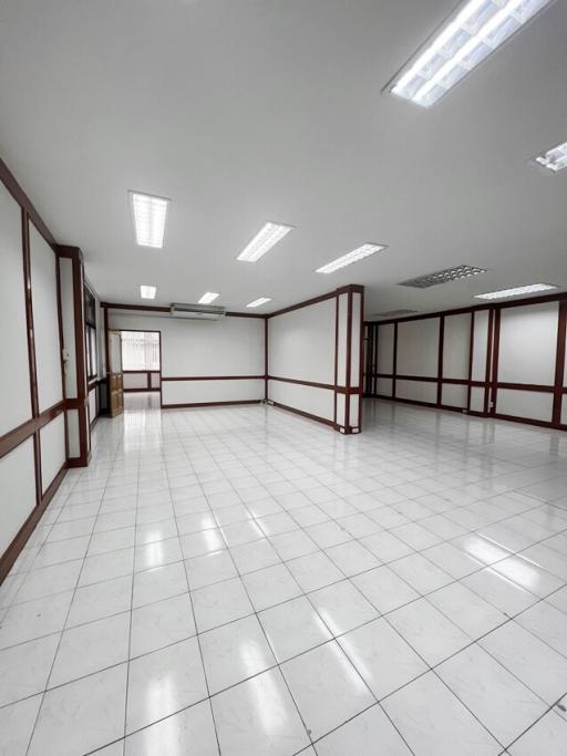 Spacious and well-lit empty commercial space with white tiling and fluorescent lighting