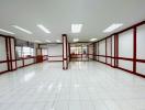 Spacious empty commercial space with white tiled flooring and red accents