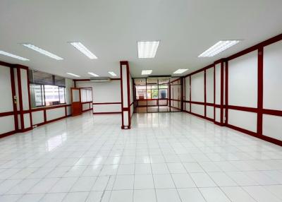 Spacious empty commercial space with white tiled flooring and red accents