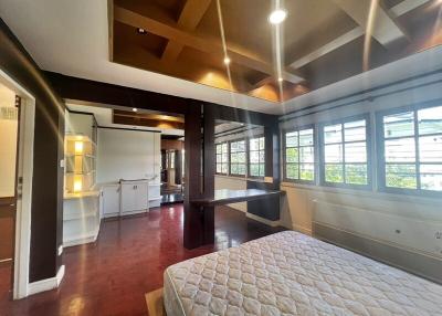 Spacious bedroom with wood beam ceiling and attached open-plan bathroom