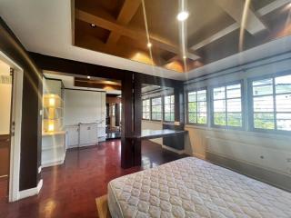 Spacious bedroom with wood beam ceiling and attached open-plan bathroom