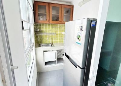 Compact kitchen with green tile backsplash and modern appliances