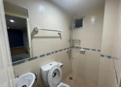 Spacious tiled bathroom with toilet and shower area