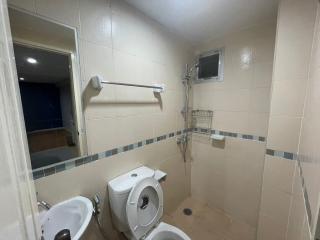 Spacious tiled bathroom with toilet and shower area