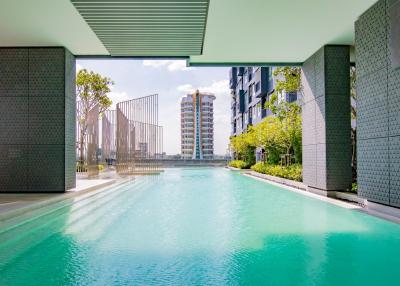 Modern residential building viewed from a luxurious pool area with clear blue water