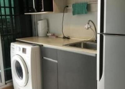 Compact kitchen with modern appliances including refrigerator and washing machine
