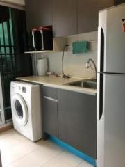 Compact kitchen with modern appliances including refrigerator and washing machine