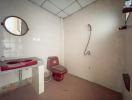 Spacious bathroom with a red sink and toilet