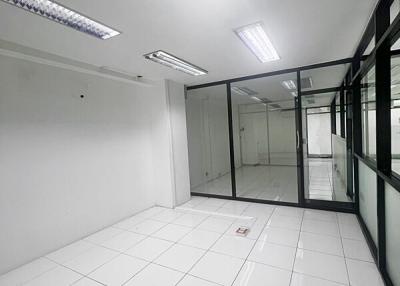 Spacious empty commercial space with tiled flooring and bright fluorescent lighting