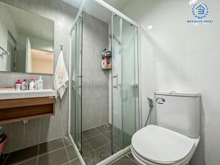 Modern bathroom with glass shower enclosure, toilet, and wooden vanity