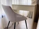 Minimalistic bedroom interior with a modern chair and desk by a window with sheer curtains