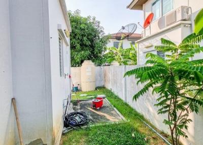 Narrow outdoor side yard of a home with grass, fencing, and some outdoor items