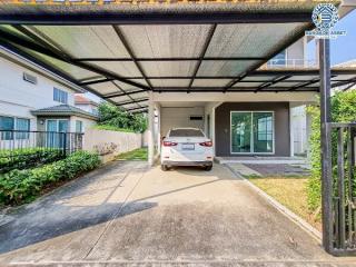 Spacious driveway with a carport and greenery