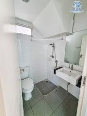 Modern white tiled bathroom with shower, toilet and sink