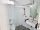 Modern white tiled bathroom with shower, toilet and sink
