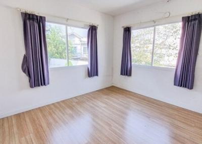 Bright empty bedroom with wooden flooring and large windows with purple curtains