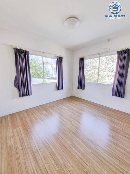 Bright empty bedroom with wooden flooring and large windows with purple curtains