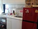 Compact kitchen with white cabinetry and red refrigerator