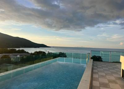 Infinity pool with a scenic view of the ocean and mountains at sunset