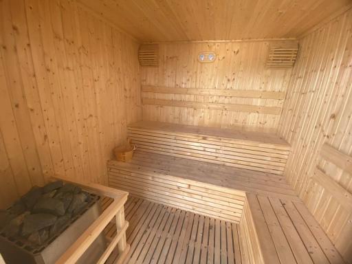 Wooden home sauna with tiered seating and stone heater