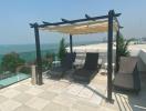 Sunny rooftop terrace with sea view, sun loungers, and pergola