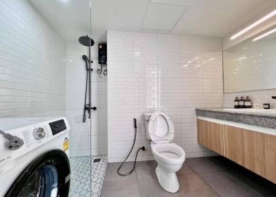 Modern spacious bathroom with white tiles and laundry machine