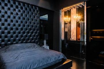 Luxurious dark-toned bedroom with tufted headboard and elegant lighting
