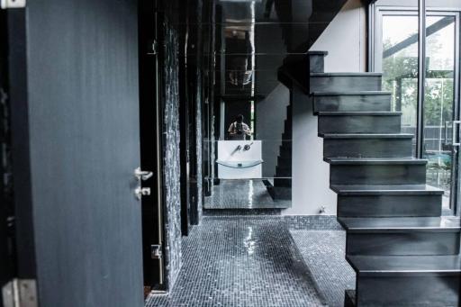 Modern interior with black tiled flooring and a sleek metal staircase leading to upper level