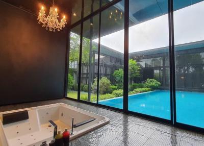 Indoor spa area with jacuzzi overlooking the pool and garden through floor-to-ceiling windows