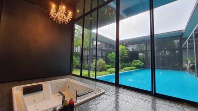 Indoor spa area with jacuzzi overlooking the pool and garden through floor-to-ceiling windows