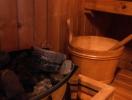 Cozy wooden sauna with stone heater and wooden bucket