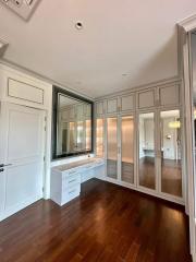 Spacious bedroom with mirrored closet doors and hardwood flooring