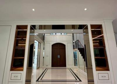 Elegant entrance hall with polished floor tiles, sophisticated lighting, and a grand wooden door