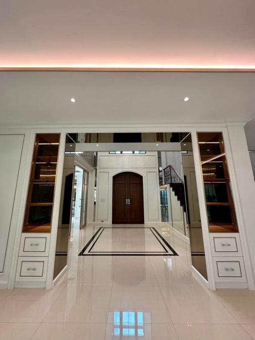 Elegant entrance hall with polished floor tiles, sophisticated lighting, and a grand wooden door