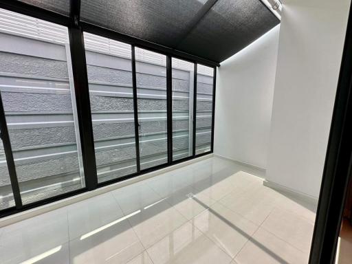 Bright enclosed sunroom with large windows and tiled flooring