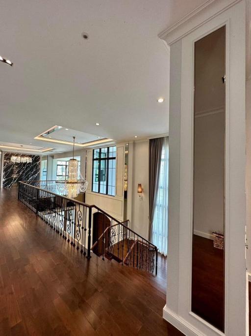 Elegant interior view of a home showcasing wooden flooring, wrought-iron railing, and chandelier