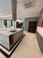 Spacious modern kitchen with center island and staircase in background