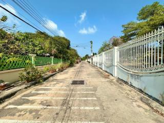 Paved road with gates leading to residential properties under a clear blue sky