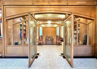 Elegant wooden double doors opening into a grand entryway with terrazzo flooring