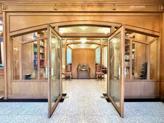 Elegant wooden double doors opening into a grand entryway with terrazzo flooring