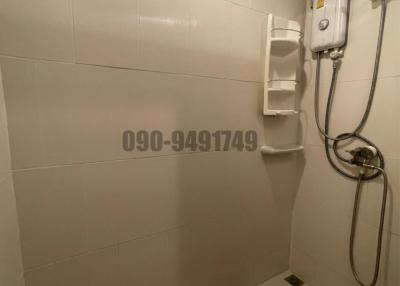 Compact white-tiled bathroom with electric water heater